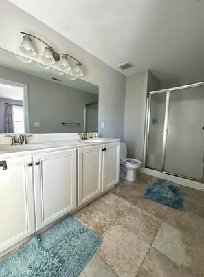A modern bathroom with a large vanity, a shower enclosure, and a mirror above the sink.