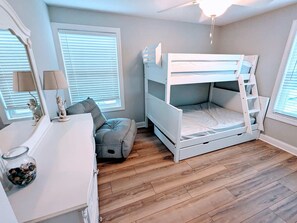 A bedroom with a bunk bed, a dresser, a mirror, and a window with blinds.