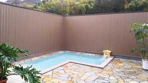 A swimming pool with stone tiles, surrounded by a wooden fence, and a potted plant. - Izuhatake Onsen Seizan (Izunokuni)