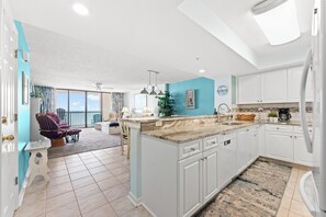 Una cocina moderna con armarios blancos, encimera de mármol y una isla grande.