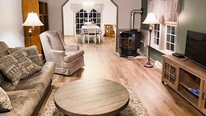 A cozy living room with a sofa, armchair, round coffee table, and a fireplace. - FOOTHILLS LOOKOUT INN -Come home to Montana! (Havre)