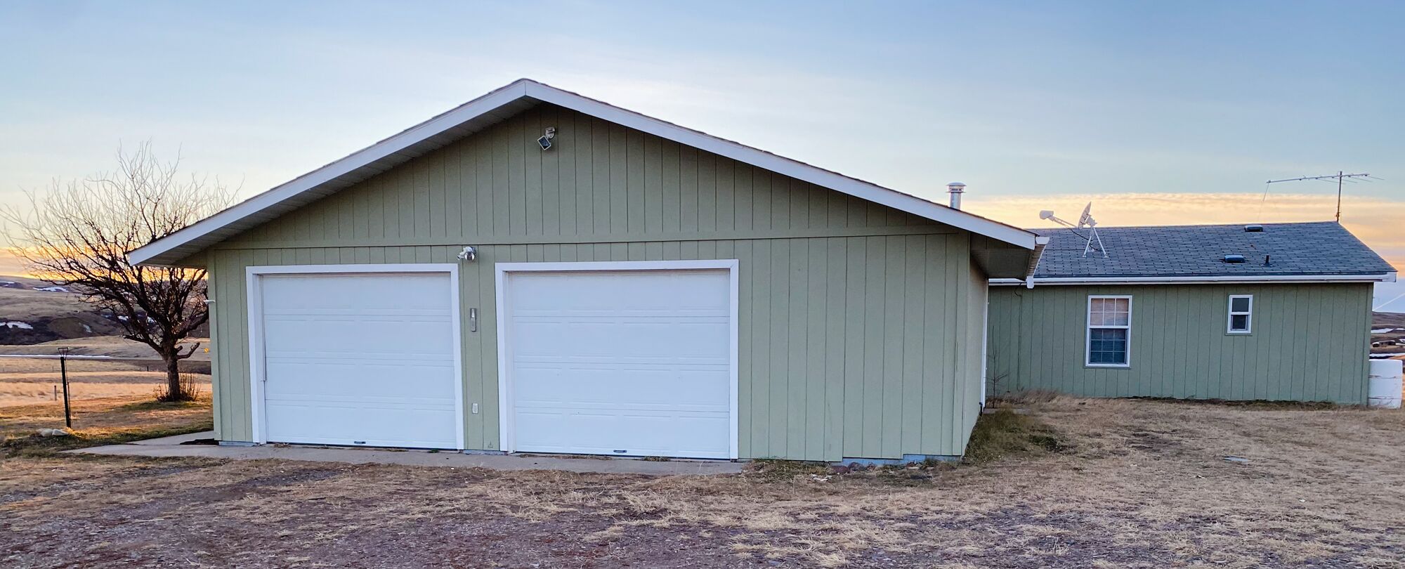 A single-story building with two garage doors, a small attached shed, and a sloped roof.
