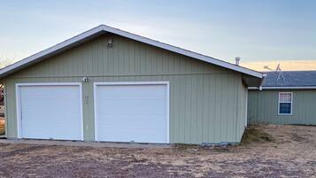 A single-story building with two garage doors, a small attached shed, and a sloped roof.