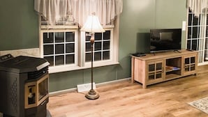 A living room with a wood-burning stove, a television, and a cabinet. - FOOTHILLS LOOKOUT INN -Come home to Montana! (Havre)