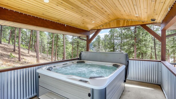 Un jacuzzi en un espacio exterior cubierto con vista a un bosque.