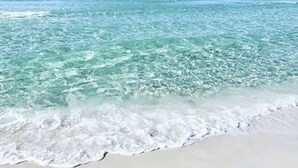 Een strand met helder turquoise water en wit zand.
