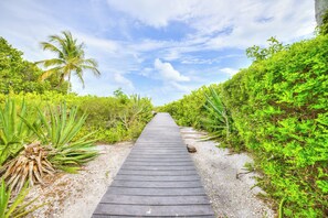 A wooden pathway leading through a tropical garden with dense foliage on both sides. - Sandals D | Luxury Beachfront Living on Sanibel Island (Sanibel)