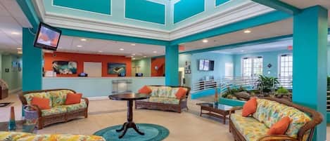 A lobby with wicker furniture, a reception desk, and a staircase.