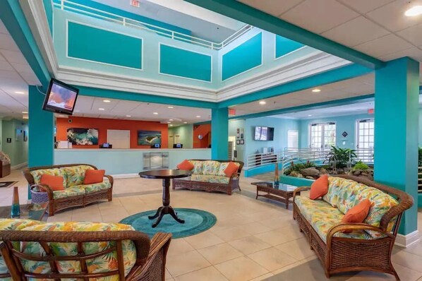 A lobby with wicker furniture, a reception desk, and a staircase.