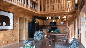 Ein Interieur einer Holzhütte mit Essbereich, Küche und einem großen Wandgemälde eines Bären.