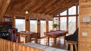Eine Holzhütte mit Billardtisch, Kicker und einem Spielbereich inklusive NASCAR-Spiel.