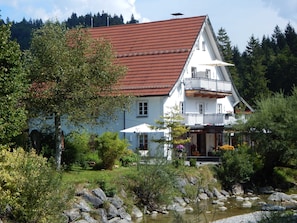 A two-story house with a red roof, white walls, and a balcony.