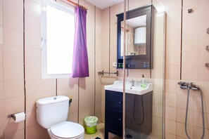 Un baño pequeño con inodoro, lavamanos y ducha.