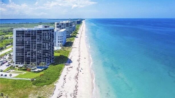 A coastal hotel with multiple buildings, a beach, and a clear view of the ocean.