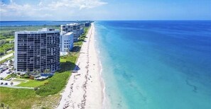 A coastal hotel with multiple buildings, a beach, and a clear view of the ocean.