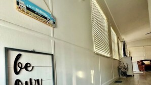 A hallway with a staircase, a framed sign saying "be our guest," and a decorative item above it.