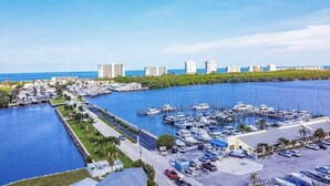 A marina with boats docked, a parking area, and buildings in the background.
