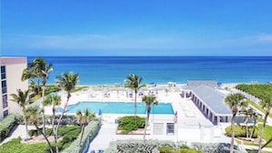 A resort with a swimming pool, palm trees, and a view of the ocean.