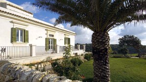 A white building with green shutters, a stone wall, and a palm tree. - Nice apartment with private terrace. Shared pool. In Donnafugata, Sicily (Donnafugata)