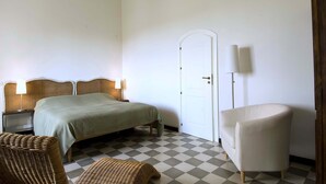 A bedroom with a bed, two bedside tables, a chair, a door, and a lamp. - Nice apartment with private terrace. Shared pool. In Donnafugata, Sicily (Donnafugata)