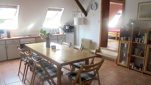 A kitchen with a wooden table and chairs, a coffee maker, and a clock on the wall. - Apartment - For Güstrow: Apartment Bergfeld (Lalendorf)
