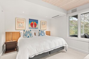 A modern bedroom with a large bed, bedside tables, and artwork on the wall.