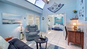 A spacious living room with a ceiling fan, a comfortable sofa, a small table with a vase, and a view of the adjacent bedroom through an open door. - 33❤️Waterfront❤️Fishing Dock❤️Close to beach❤️King Bed (BreckenridgeCorpus Christi)