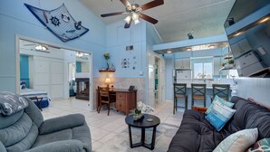 A spacious living room with a gray sofa, a black couch, and a dining area with a table and chairs. A ceiling fan and a decorative wall hanging are visible. - 33❤️Waterfront❤️Fishing Dock❤️Close to beach❤️King Bed (BreckenridgeCorpus Christi)