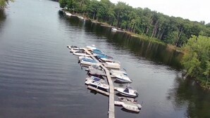Un quai où sont amarrés plusieurs bateaux, sur une étendue d’eau calme, le tout entouré d’une végétation luxuriante.