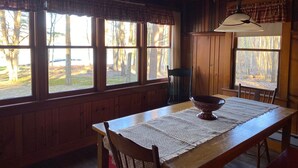 Un coin repas en bois avec une table, des chaises et un luminaire suspendu.