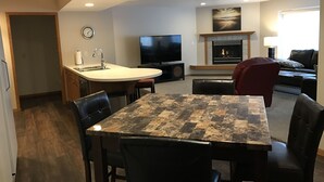 A modern living room with a dining area, a fireplace, and a television. - 5th Steele Place, LLC - Downtown Algoma Condos: Overnight or Extended Stays (Algoma)