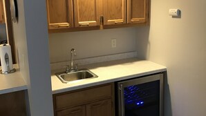 A compact kitchen with wooden cabinets, a stainless steel sink, and a built-in dishwasher. - 5th Steele Place, LLC - Downtown Algoma Condos: Overnight or Extended Stays (Algoma)