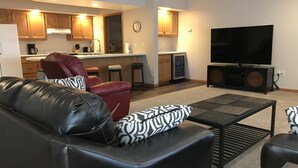 A modern living room with a leather sofa, a coffee table, and a flat-screen TV. - 5th Steele Place, LLC - Downtown Algoma Condos: Overnight or Extended Stays (Algoma)