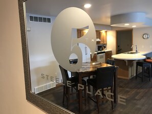 Una cocina moderna con una isla central, sillas de madera y horno empotrado.