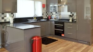 A modern kitchen with grey cabinets, a stainless steel range hood, a microwave, and a built-in oven. - 3 bedroom accommodation in Otterburn, near Bellingham (Otterburn, near Bellingham)