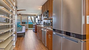 Una cocina moderna con electrodomésticos de acero inoxidable, armarios de madera y una estantería empotrada.