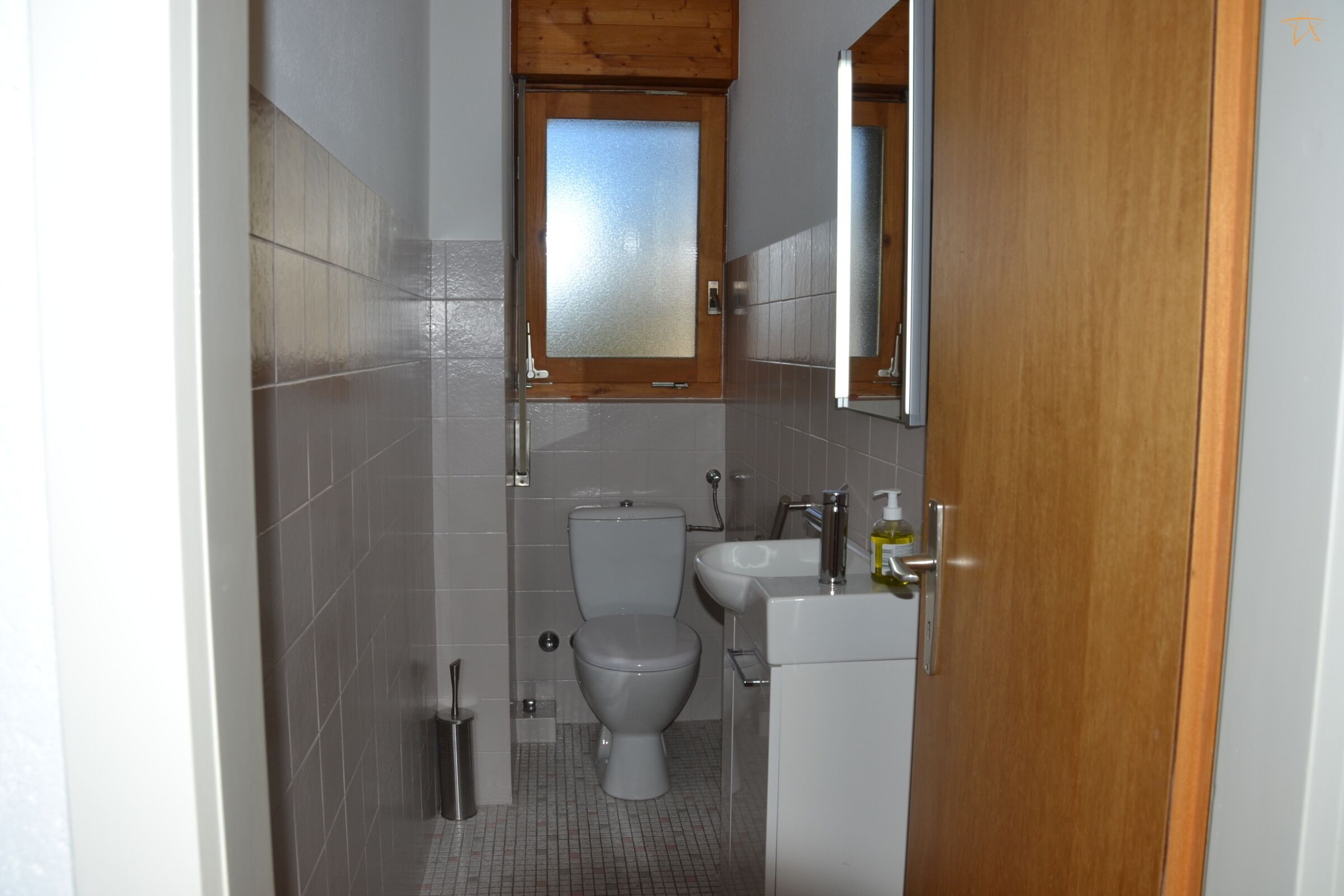 Un baño pequeño con inodoro, lavamanos y espejo.