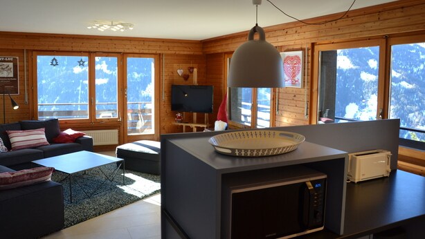 Una sala de estar moderna con un sofá, una mesa de centro y una zona de cocina con microondas y tostadora.