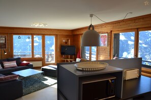 Un salon moderne comprenant un canapé, une table basse et un coin cuisine équipé d’un four à micro-ondes et d’un grille-pain.