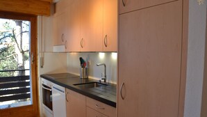 Una cocina moderna con armarios de madera, un lavamanos de acero inoxidable y un horno empotrado.