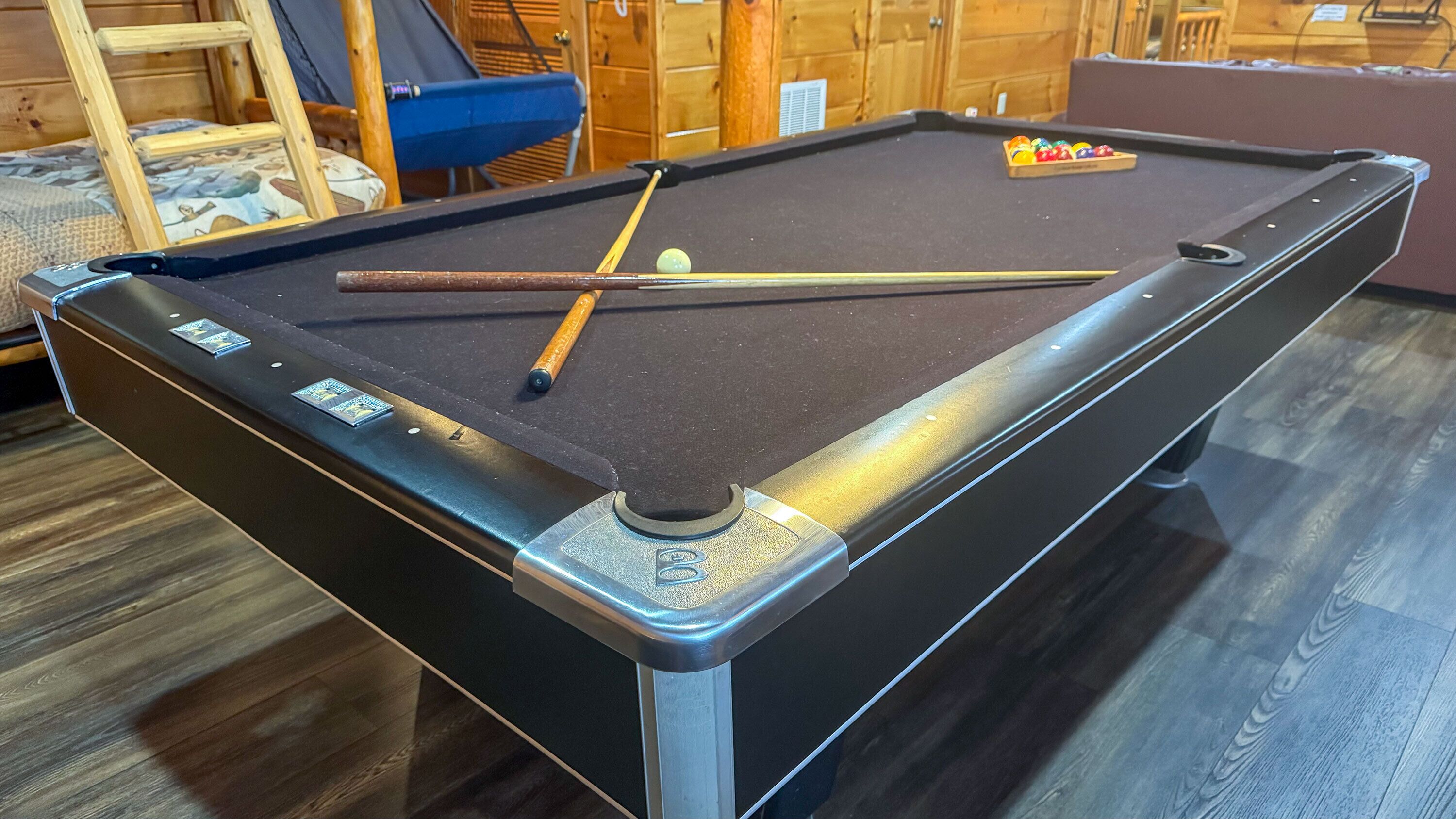 A pool table with a cue stick, a billiard ball, and a set of balls.
