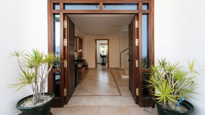 A hallway with wooden doors, potted plants, and a tiled floor leading to a room with a table and chairs. - Villa Jimena by Mabiente Properties by Mabiente Properties (Mijas)