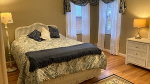 Une chambre à coucher avec un lit, une table de chevet, une lampe et une fenêtre avec des rideaux.