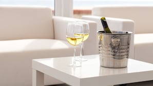 Een witte tafel met twee wijnglazen en een metalen emmer met een fles wijn.