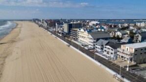 A beachside hotel with a long sandy beach, a promenade, and buildings along the shore. - Beach Cottage 1Bed & 1Bath Fully Renovated next to the Boardwalk (Ocean City)
