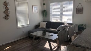 A modern living room with a sofa, a dining table with chairs, and large windows with blinds. - Beach Cottage 1Bed & 1Bath Fully Renovated next to the Boardwalk (Ocean City)