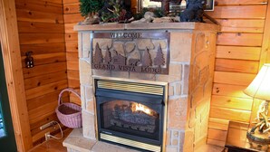 A stone fireplace with a welcome sign, a basket, and a lamp. - Grand Vista Lodge - Cabin (Sevierville)