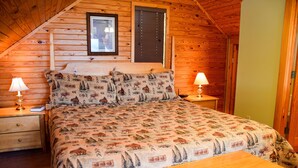 A wooden cabin bedroom with a bed, two bedside tables, and a nightstand. - Hiker's Point - Cabin In The Smokies (Sevierville)
