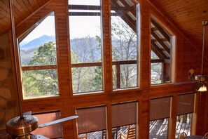 A cabin with large windows, wooden interior, and a view of mountains and trees. - Hiker's Point - Cabin In The Smokies (Sevierville)