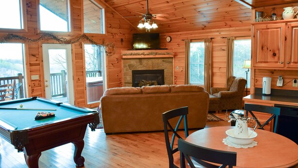 A cozy cabin interior with a pool table, a sofa, a fireplace, and wooden walls. - Unforgettable - Cabin (Sevierville)